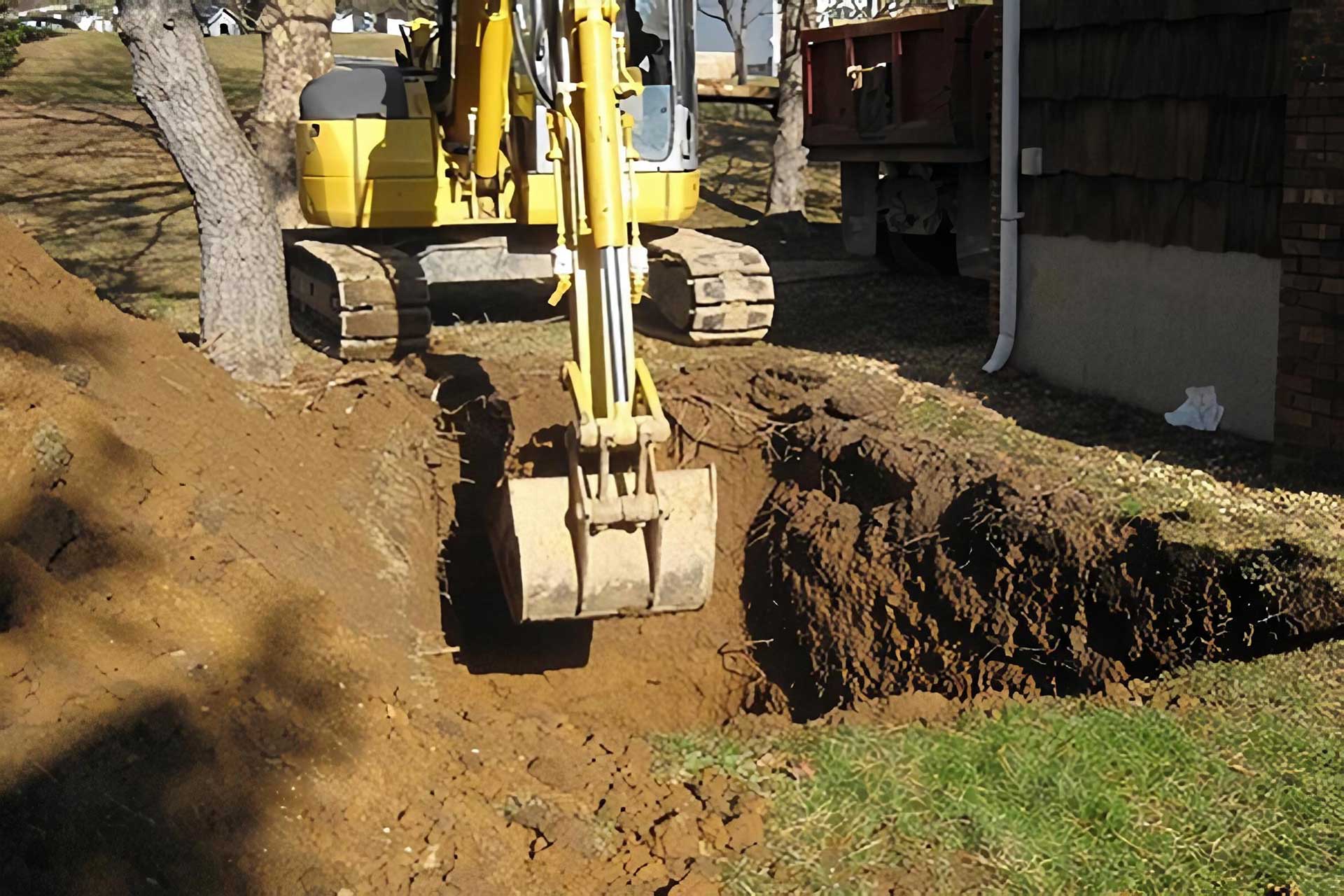 Excavator digging in the ground next to a house