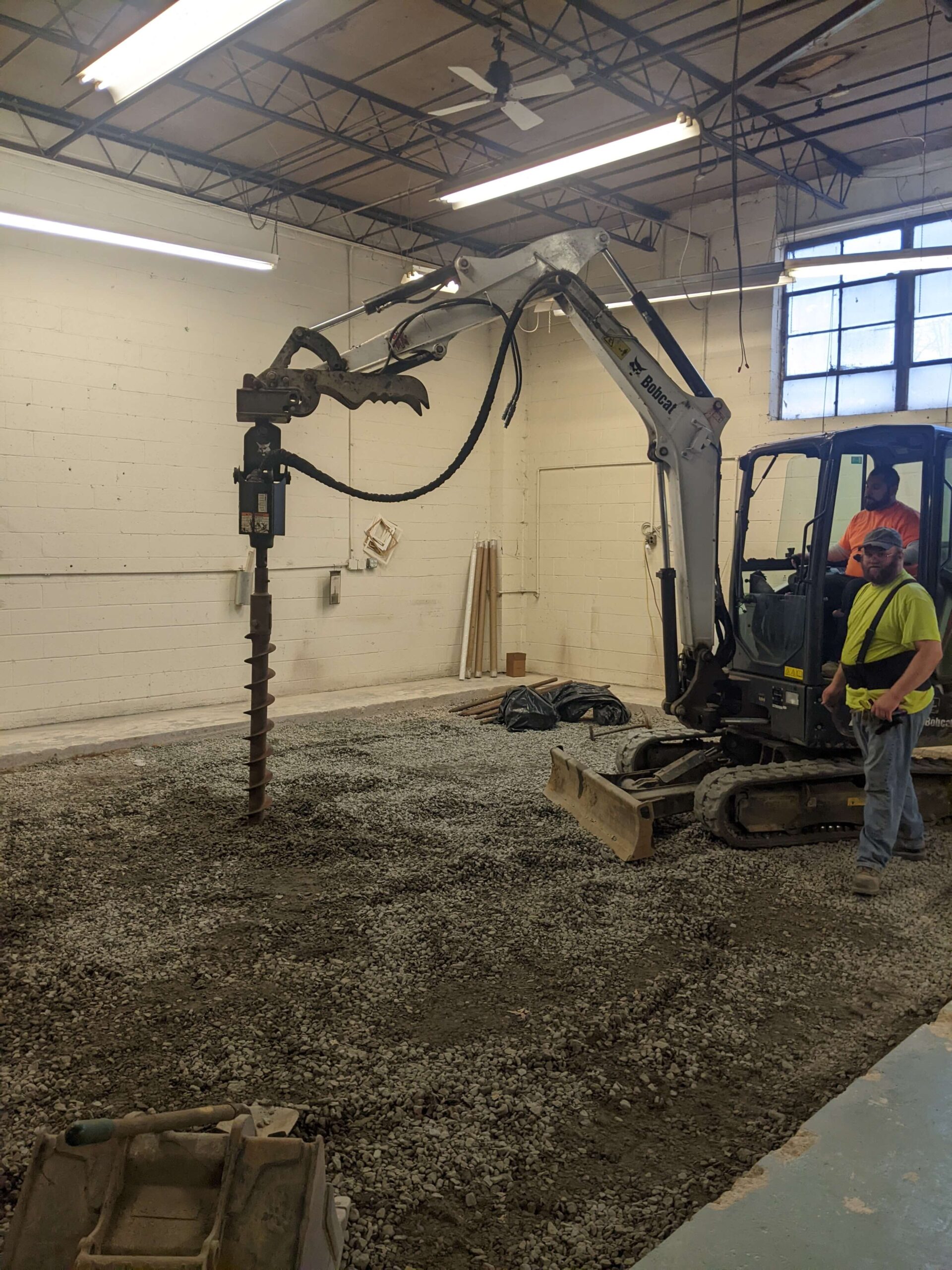Excavator drilling into gravel floor